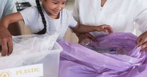 Child sorting plastics with grandparents encouraging recycling habits