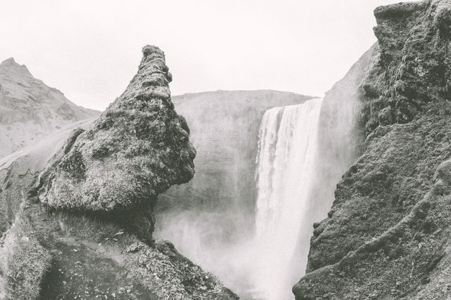 Monochromatic depiction of a powerful waterfall flowing between steep, rocky cliffs in natural terrain. Ideal for travel blogs, nature enthusiasts, conservation campaigns, posters, and photographic art collections highlighting natural wonders.