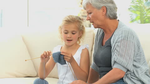 Grandmother Teaching Granddaughter Knitting at Home