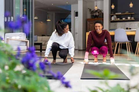 Diverse women placing yoga mats at patio entrance for home workout and wellness routine