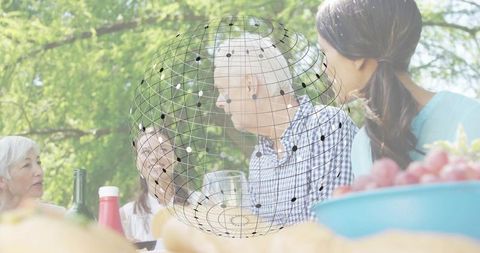 Multi-generation family gathering for outdoor picnic with senior man and digital globe overlay