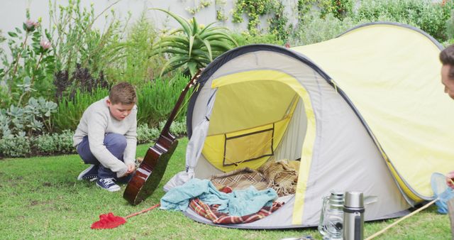 Caucasian father with son preparing camp with tent in garden. family spending time at home.