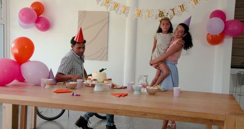 Family enjoying home birthday celebration with cake and party hats