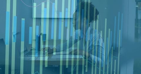 Focused business analyst reviewing financial data on laptop with translucent graphs overlay