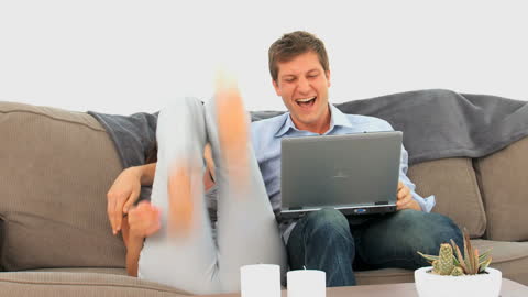 Couple Laughing Hysterically While Watching Laptop at Home