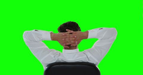 Businessman Relaxing with Hands Behind Head Against Green Screen