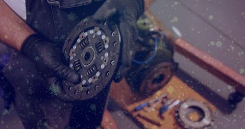 Automotive mechanic examining clutch plate with protective gloves