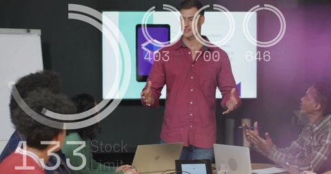 Young professional presenting at boardroom meeting with laptops and slide screen