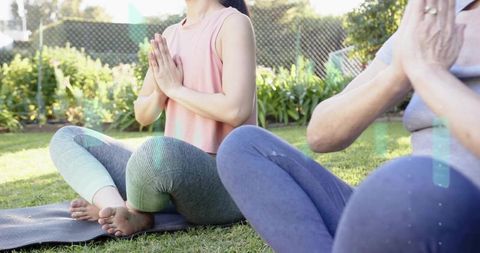 Mother and adult daughter practicing outdoor meditation on lawn, mindful wellness routine