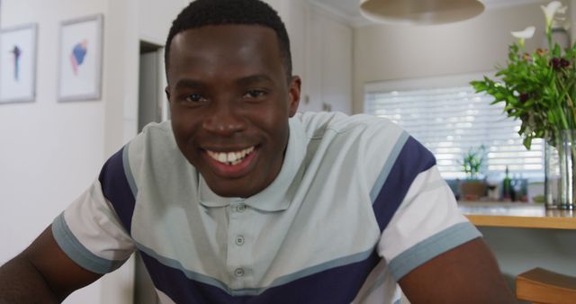 Image of happy african american man making image call smiling and waving to camera in kitchen. Communication, happiness, domestic life and inclusivity concept.