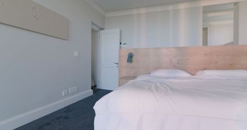 Minimalist modern bedroom with light wood headboard white linens teal wall lamp calm