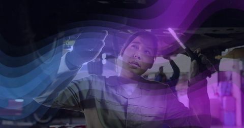 Female auto mechanic inspecting car undercarriage