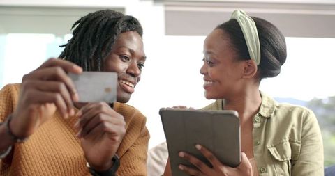 Smiling African American Couple Sharing Tablet and Smartphone While Browsing Together