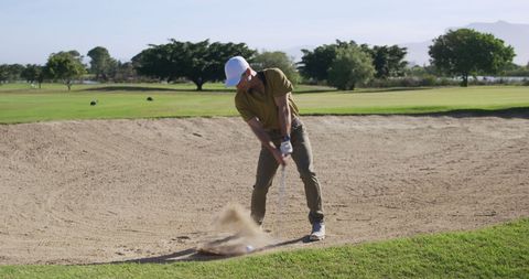 Determined Male Golfer Executing Sand Bunker Shot on Sunny Golf Course