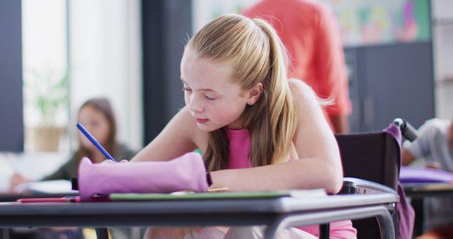 Concentrated Girl Writing in Classroom with Others Working in Background - Download Free Stock Images Pikwizard.com