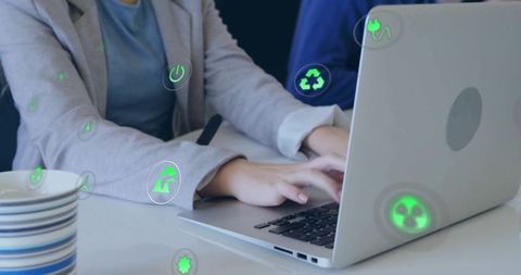 Businesswoman typing on laptop with green eco icons overlay representing sustainability
