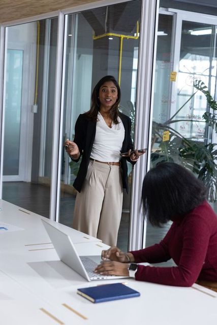 Business leader presenting strategy in glass-walled office during collaborative meeting