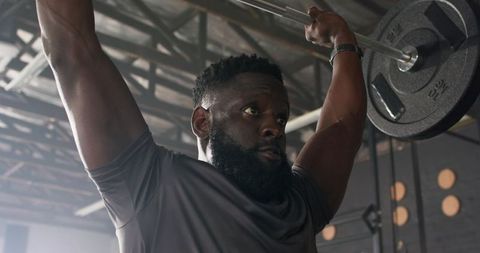 Male athlete lifting barbell in gym focused on strength