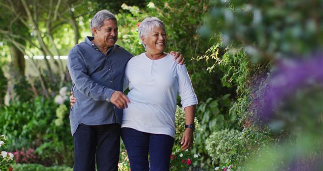 Image of happy biracial senior couple embracing and walking in garden. active retirement lifestyle, senior relationship and spending time together concept.