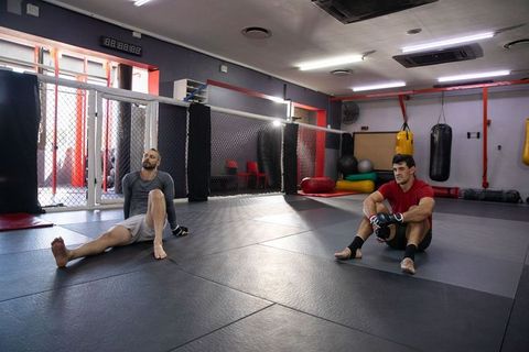 Sitting on mats mma fighters resting after sparring wearing rashguards and gloves
