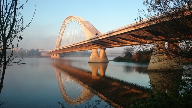 Modern Arch Bridge Reflecting in Calm River at Sunrise - Download Free Stock Photos Pikwizard.com