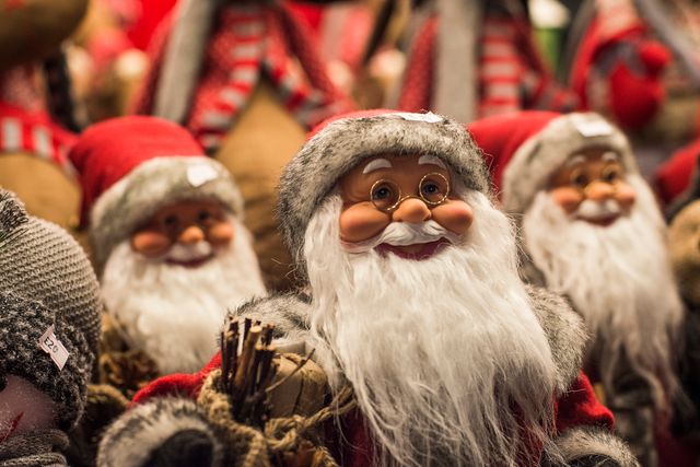 Collection of Santa Claus figures wearing red and white attire at a Christmas market. Perfect for promoting holiday events, Christmas sales, festive advertisements, and seasonal decor ideas.