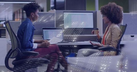 Businesswomen collaborating with digital interface overlays in modern office