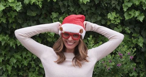 Smiling Woman in Santa Hat and Reindeer Glasses Outdoors