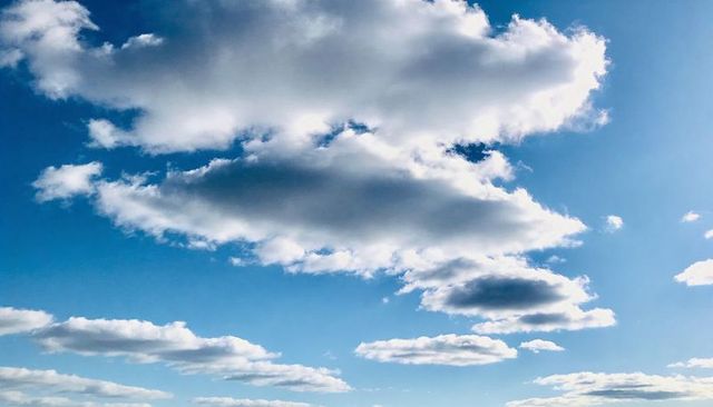 Layered cumulus clouds forming horizontal bands across bright blue sky