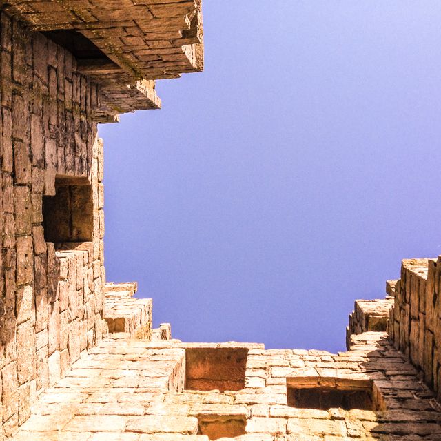 An upward view featuring ancient stone ruins with parts of the blue sky visible through architectural gaps. Suitable for use in articles about history, architecture, travel, and cultural heritage. Perfect for use in brochures, educational materials, and heritage site promotions.