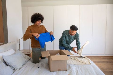 Friends unpacking clothes in cozy bedroom setting