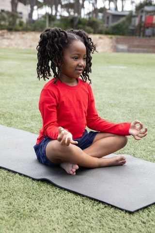 Child Practicing Yoga Meditation Outdoors on Lawn