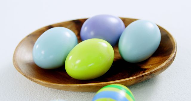 Colorful Easter eggs are arranged in a wooden bowl, with copy space. Their pastel colors suggest a festive springtime or Easter celebration.