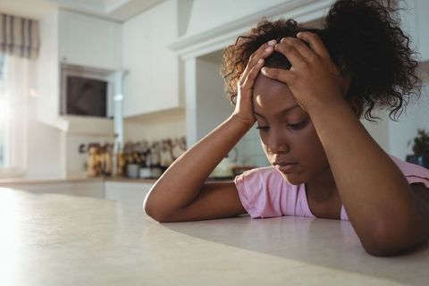 Pensive Child in Kitchen Leaning on Counter