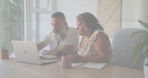 Mature couple reviewing finances and paperwork on laptop at home, planning budget together