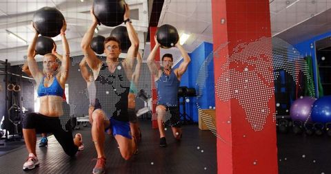 Lunging fitness class holding medicine balls overhead with digital world map overlay