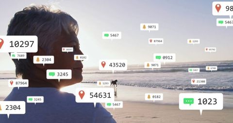 Senior woman reflects by ocean with digital notifications floating around