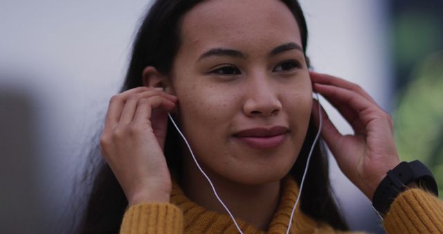 Asian woman wearing earphones listening to music and smiling - Download Free Stock Photos Pikwizard.com