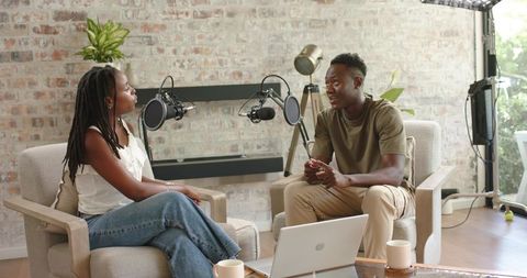 African American Co-Hosts Recording Casual Podcast Conversation in Cozy Home Studio Lounge