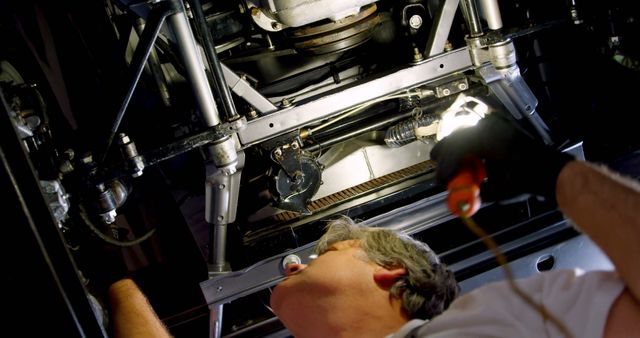 Mechanic Inspecting Car Under Carriage with Flashlight in Workshop - Download Free Stock Images Pikwizard.com