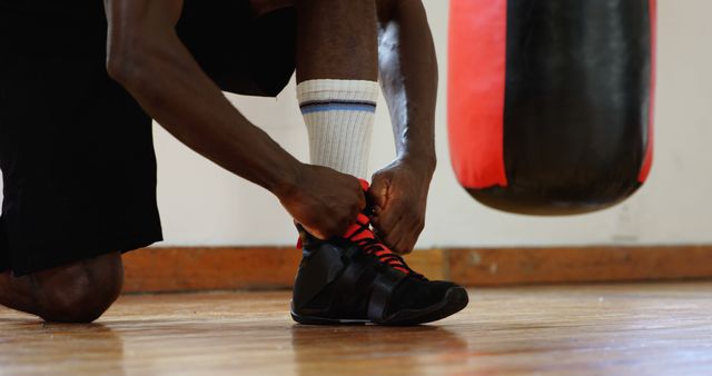 Athlete Tying Boxing Shoes Next to Red Punching Bag - Download Free Stock Images Pikwizard.com