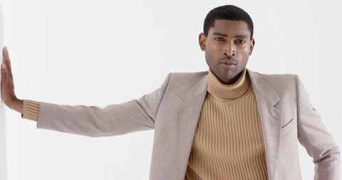 Elegant model posing in beige blazer and tan turtleneck in studio