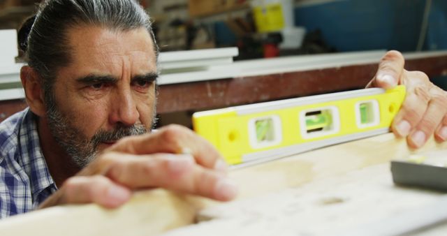 Focused Carpenter Using Spirit Level for Precision Measurement - Download Free Stock Images Pikwizard.com