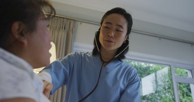 Nurse using stethoscope while examining elderly patient during in-home healthcare visit, providing personalized care and medical attention. Suitable for depicting themes of elderly care, professional healthcare services, nurse-patient interaction, and medical support in domestic setting. Ideal for health service providers, home nursing agencies, medical blogs, and educational materials.