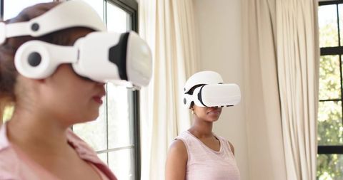 Women Exploring Virtual Reality Headsets in Bright Home Interior for Social Gaming and Training