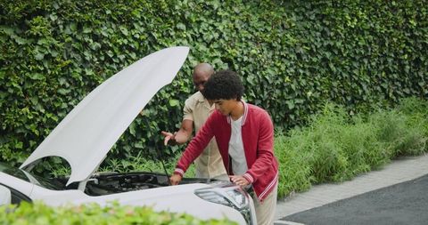 Father and son inspecting car in garden for engine maintenance