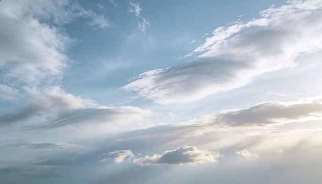 Lenticular Clouds Stretching Over Sunlit Sky Casting Soft Rays with Ethereal Cirrus Streaks