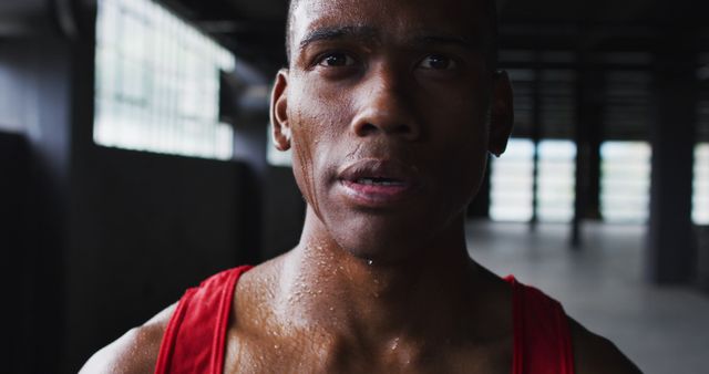 This image features an African American male athlete, drenched in sweat, showcasing determination and focus while training in a gym. It captures the essence of hard work and perseverance. This can be used in advertisements for fitness products, gym promotions, motivational posters, or health and wellness campaigns.