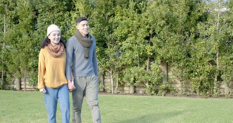 Diverse couple walking hand in hand in scenic nature