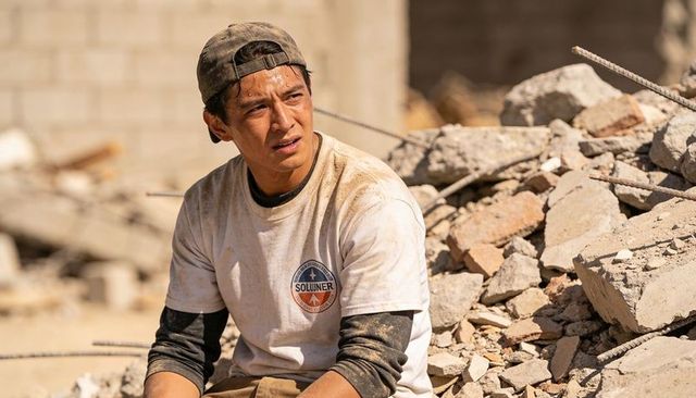 Construction worker resting on rubble and bent rebar, sweating after demolition work